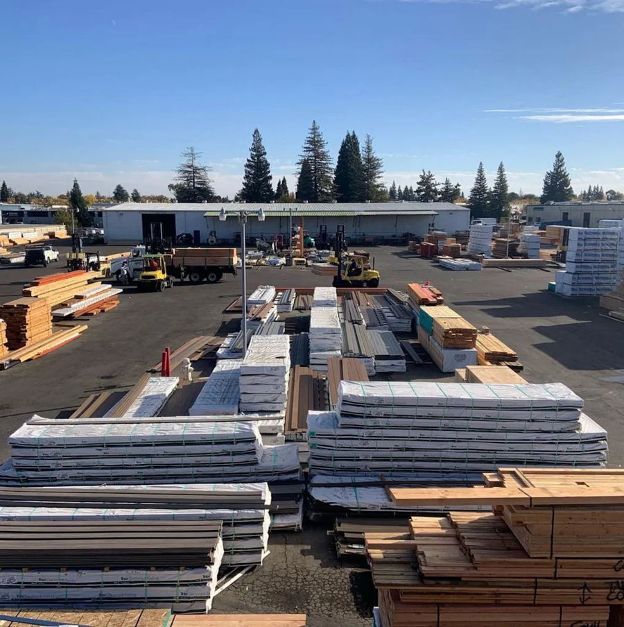 The Wayside Lumber yard in Rancho Cordova: bunks of decking and lumber stacked across the yard, forklifts loading, the warehouse behind