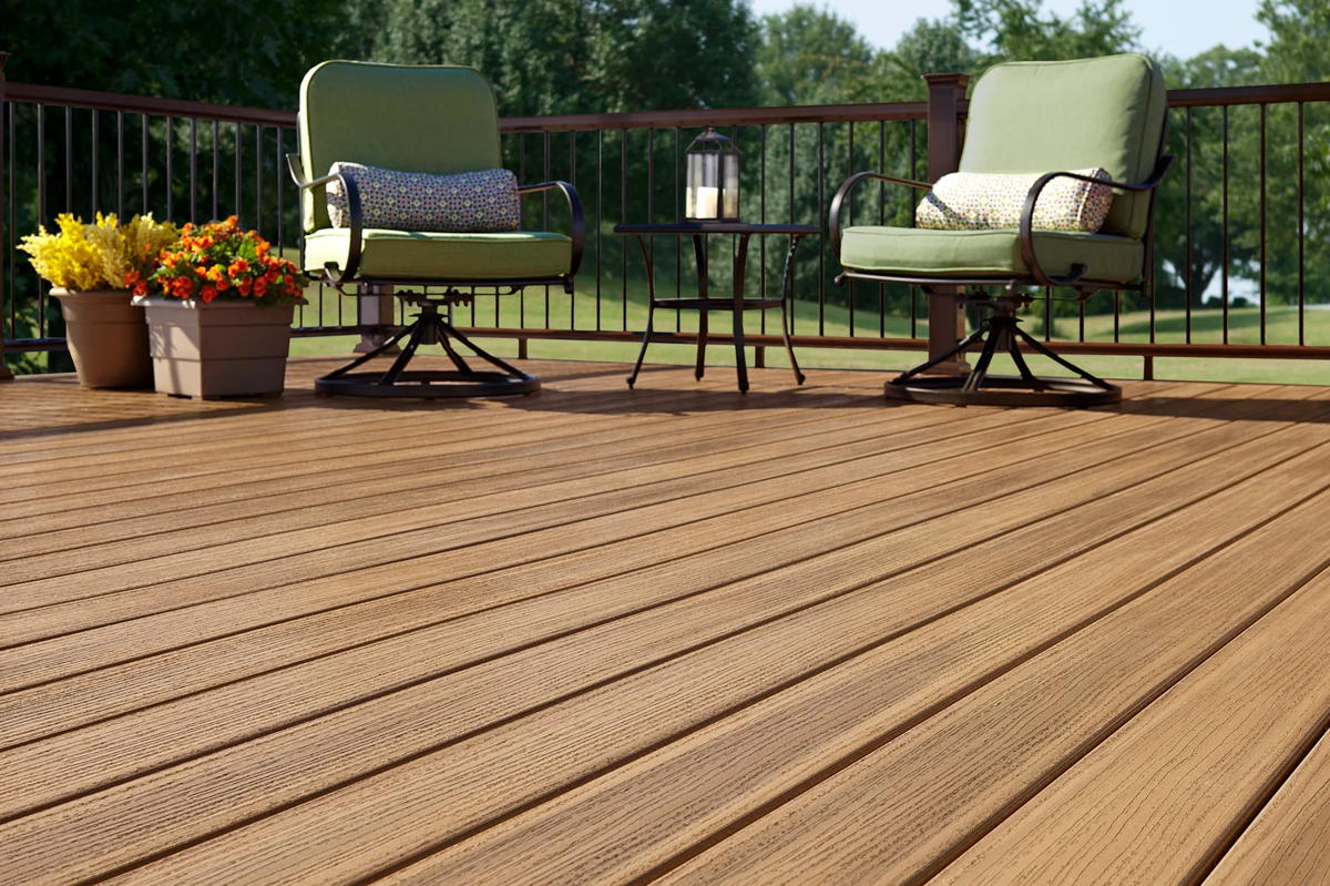 A honey-brown Fiberon deck with black metal railing, cushioned swivel chairs and a bistro table, looking out over a lawn to open water