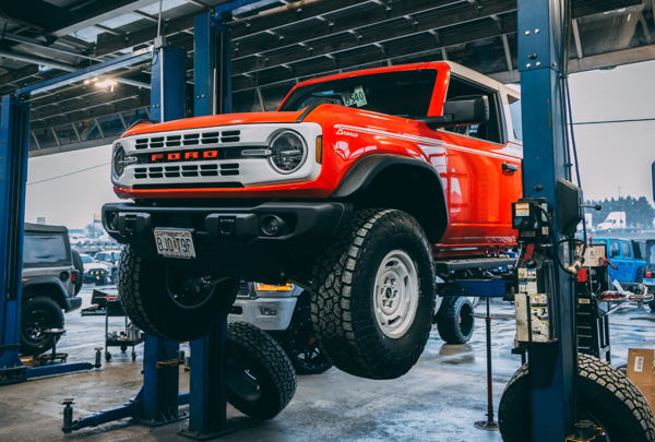 Professional technician performing post-lift alignment on Jeep Wrangler using precision equipment