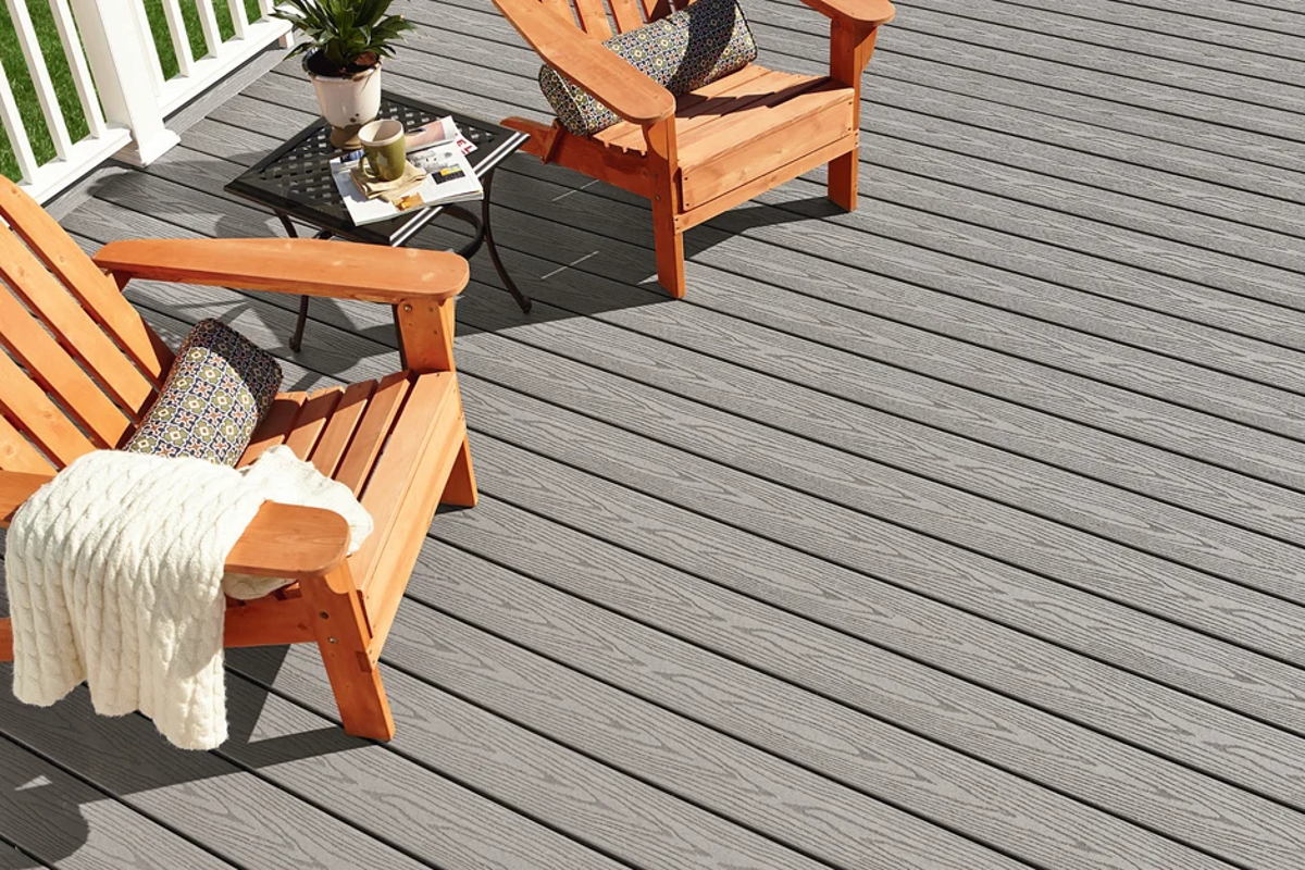 A weathered-grey Fiberon deck with cedar-toned Adirondack chairs, a knitted throw and a low table set for coffee